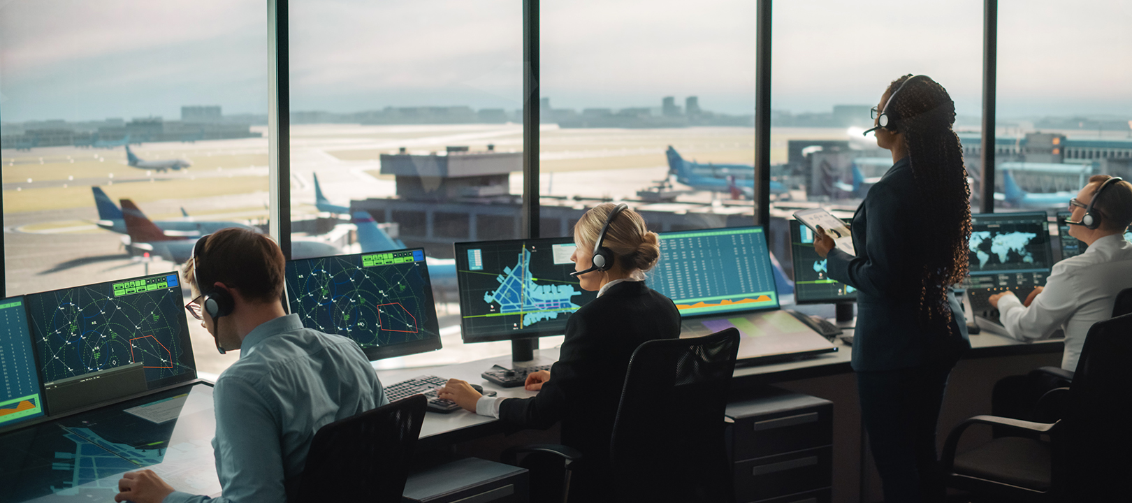 Diverse Air Traffic Control Team Working in a Modern Airport Tower. Office Room is Full of Desktop Computer Displays with Navigation Screens, Airplane Departure and Arrival Data for Controllers.